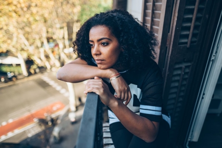 Sad woman looking out from balcony